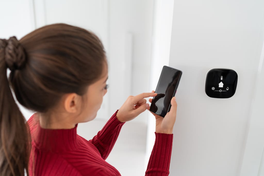 Woman controlling smart hvac system from phone. | A new HVAC Systems with Integrated Air Purification built in for the purest air. 